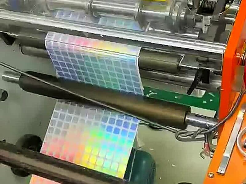 Holographic label stock running through the rollers of a printing press
