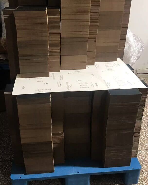 Finished corrugated cartons stacked and palletised on the factory floor, packing list laid on top, ready for collection