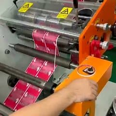 A printed label web running through the rollers of a rotary label press