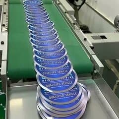 Die-cut circular pressure-sensitive labels stacked and separated coming off the conveyor